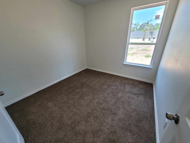 unfurnished room featuring dark colored carpet