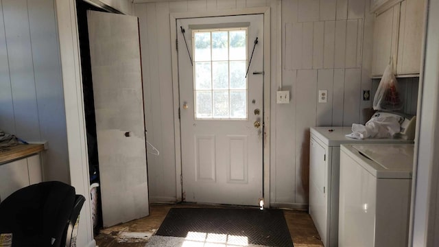 laundry room featuring cabinets, wooden walls, and washing machine and clothes dryer