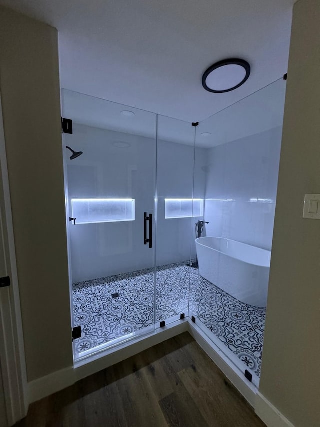 bathroom featuring wood-type flooring and shower with separate bathtub