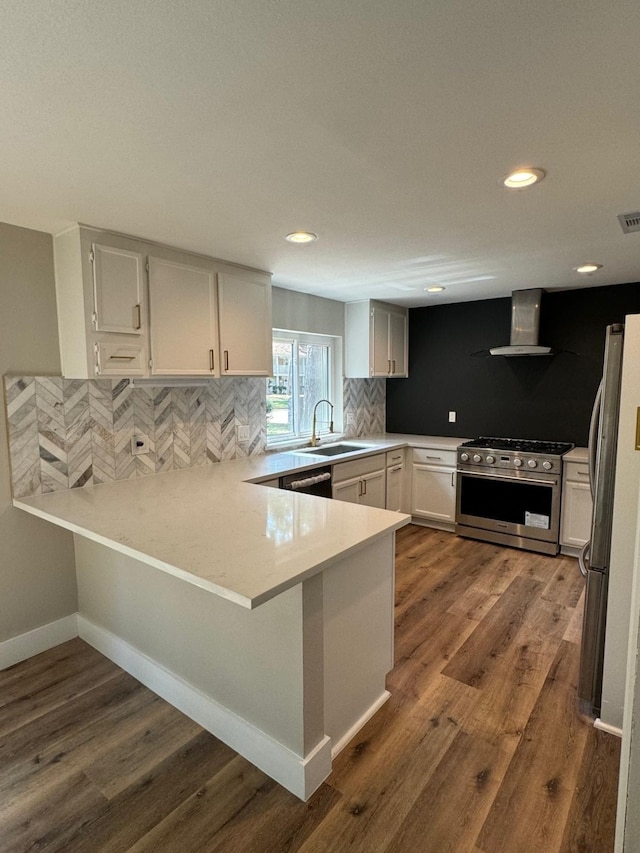 kitchen featuring white cabinetry, wall chimney range hood, dark hardwood / wood-style flooring, kitchen peninsula, and appliances with stainless steel finishes