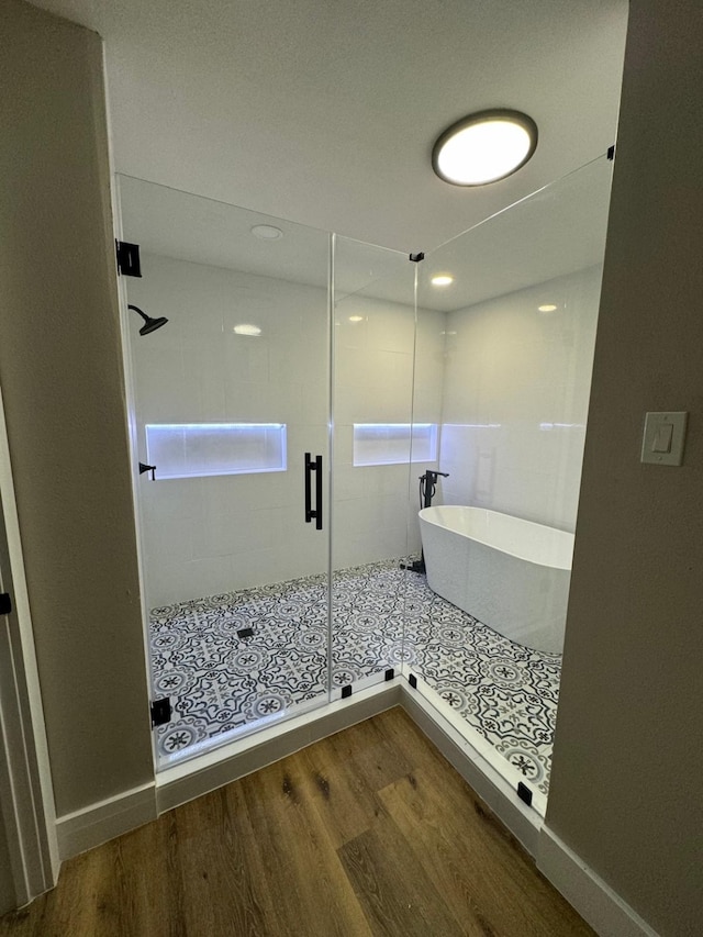 bathroom with hardwood / wood-style floors and shower with separate bathtub