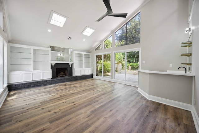 unfurnished living room featuring a skylight, ceiling fan, a brick fireplace, high vaulted ceiling, and hardwood / wood-style floors