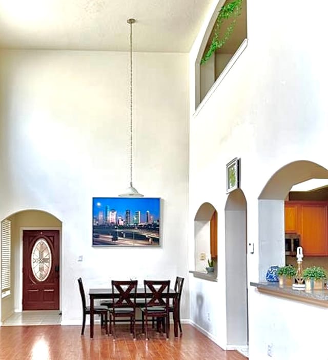 dining space featuring hardwood / wood-style flooring and a towering ceiling