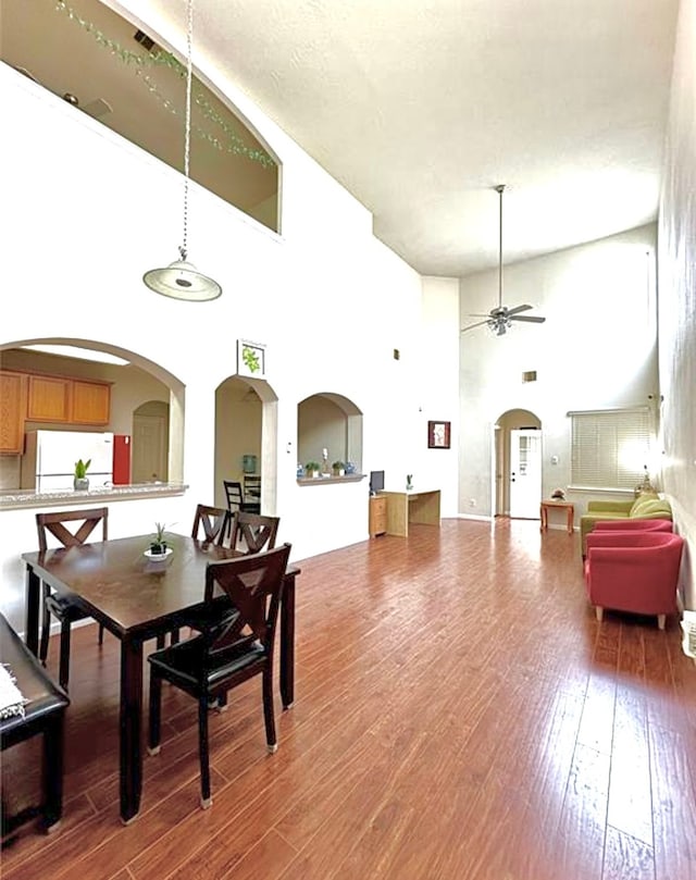 dining room with hardwood / wood-style floors, a towering ceiling, and ceiling fan