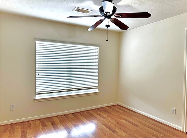 empty room with light hardwood / wood-style floors, ceiling fan, and a textured ceiling