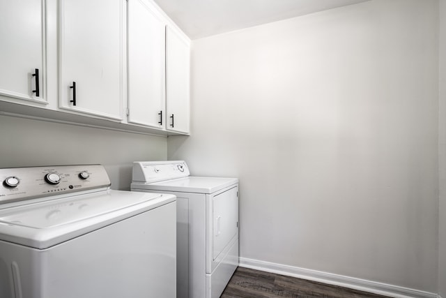 laundry room featuring dark hardwood / wood-style floors, washing machine and clothes dryer, and cabinets