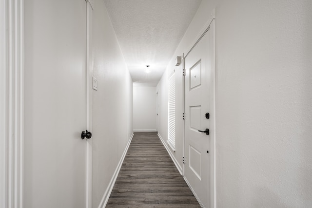 corridor with a textured ceiling and dark hardwood / wood-style floors