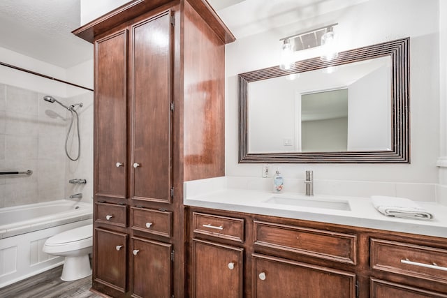 full bathroom featuring hardwood / wood-style flooring, vanity, toilet, and tiled shower / bath