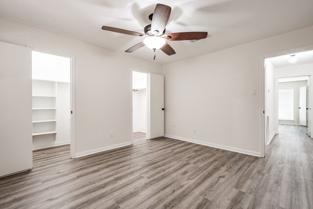 unfurnished bedroom with light hardwood / wood-style floors, a spacious closet, ceiling fan, and a closet