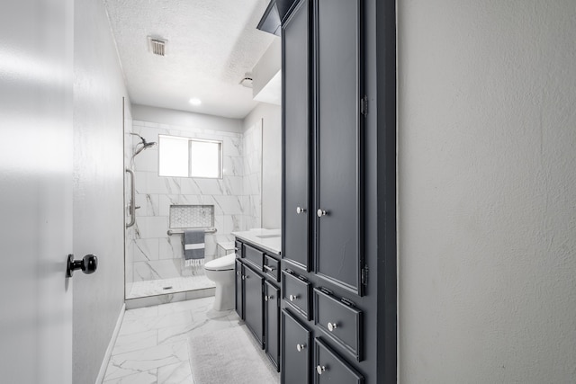 bathroom with tiled shower, a textured ceiling, vanity, and toilet