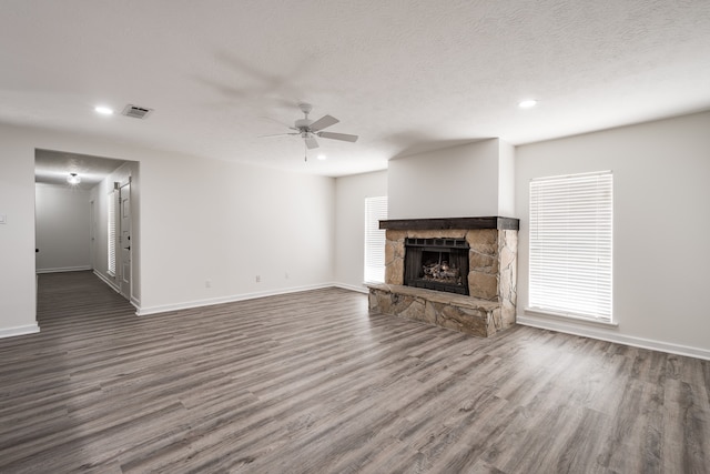 unfurnished living room featuring a textured ceiling, a fireplace, dark hardwood / wood-style floors, and ceiling fan