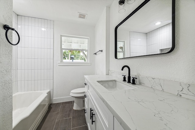 full bathroom featuring tiled shower / bath, vanity, and toilet