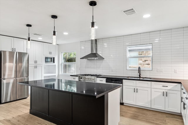 kitchen with a kitchen island, pendant lighting, stainless steel appliances, and light hardwood / wood-style flooring