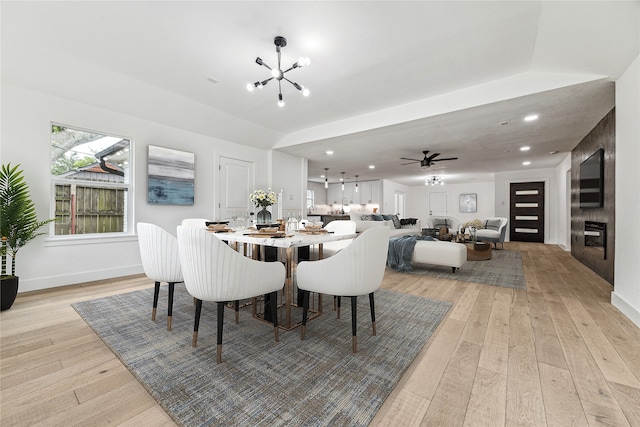 dining room with ceiling fan with notable chandelier and light hardwood / wood-style floors