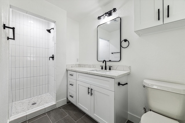 bathroom with a tile shower, tile patterned floors, vanity, and toilet