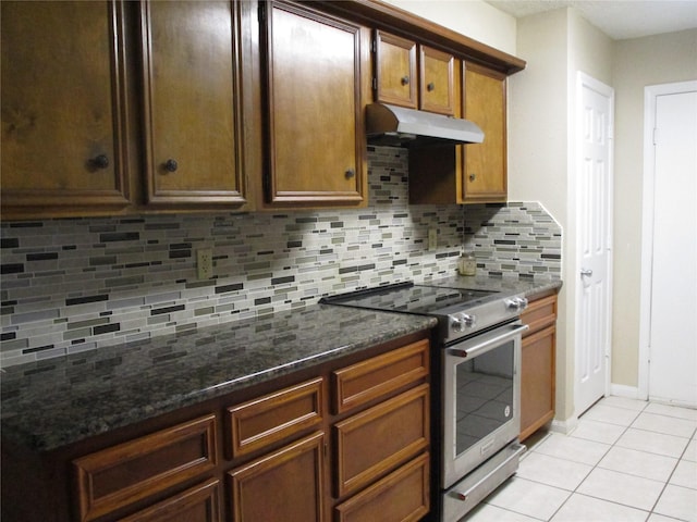 kitchen featuring light tile patterned floors, electric range, dark stone counters, and backsplash