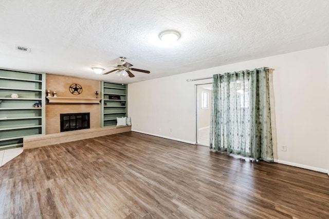 unfurnished living room featuring ceiling fan, dark hardwood / wood-style flooring, and a textured ceiling