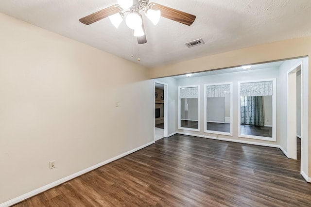 empty room featuring dark hardwood / wood-style floors, ceiling fan, and a textured ceiling