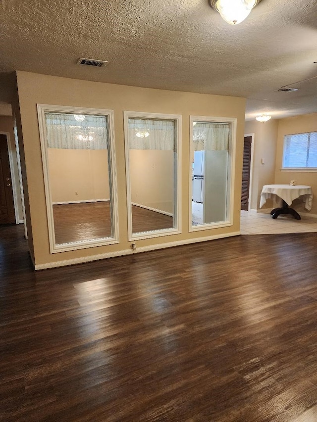 empty room featuring a textured ceiling and dark hardwood / wood-style floors