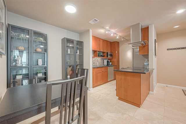 kitchen with exhaust hood, stainless steel appliances, backsplash, and light tile patterned floors