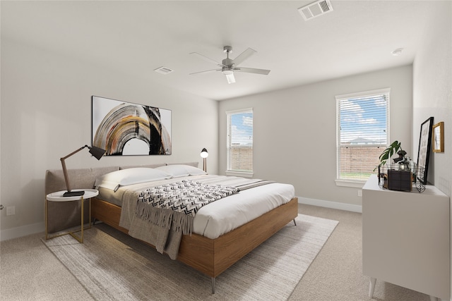 bedroom featuring multiple windows, light colored carpet, and ceiling fan