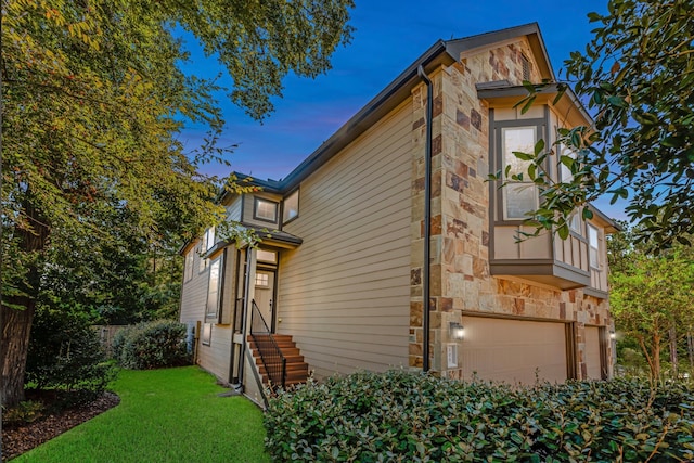 property exterior at dusk featuring a lawn and a garage