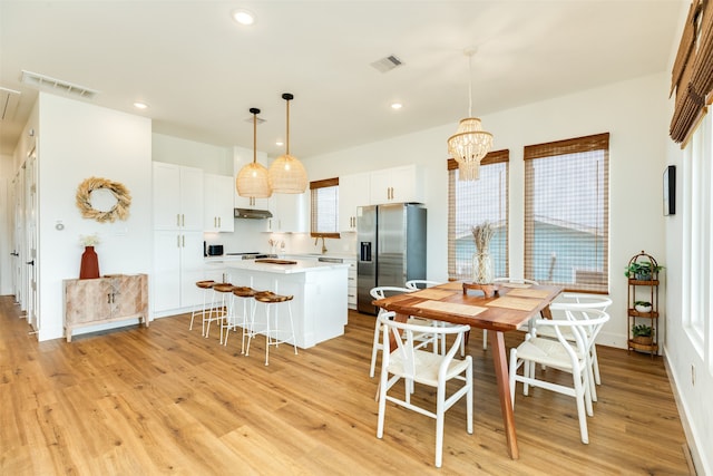 dining space featuring light hardwood / wood-style floors and an inviting chandelier