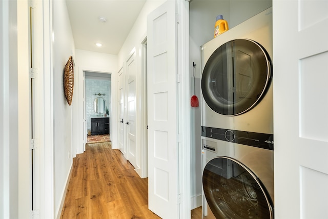 laundry room with stacked washer and dryer and light hardwood / wood-style flooring