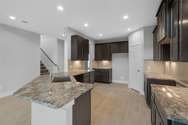 kitchen featuring light hardwood / wood-style floors, sink, decorative backsplash, and light stone counters