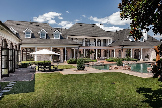 rear view of house with a patio, a lawn, and a balcony