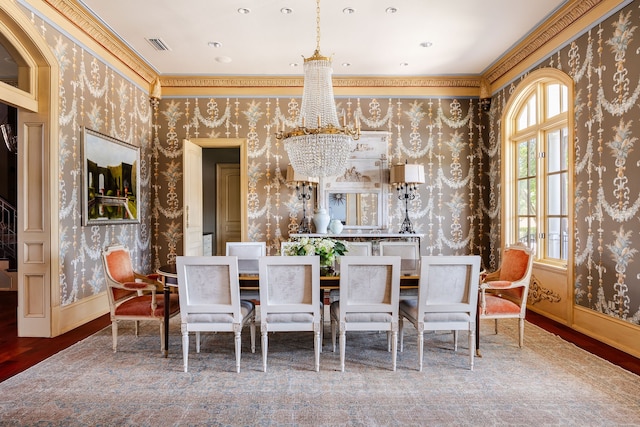 dining space with hardwood / wood-style flooring, crown molding, and a notable chandelier