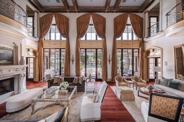 living room featuring coffered ceiling, a high ceiling, beam ceiling, hardwood / wood-style floors, and a premium fireplace