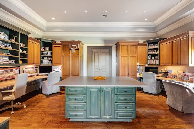 kitchen featuring a kitchen island, built in desk, a tray ceiling, crown molding, and dark hardwood / wood-style flooring