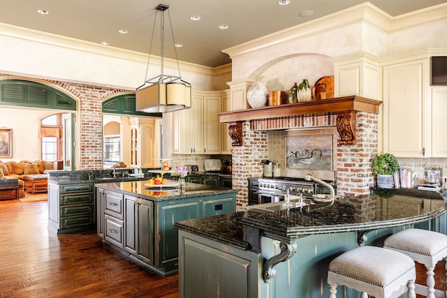 kitchen featuring dark hardwood / wood-style floors, hanging light fixtures, a kitchen island, crown molding, and dark stone countertops