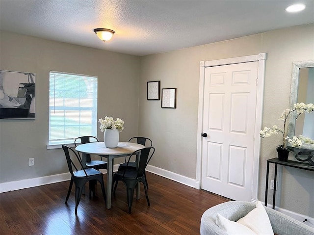 dining room featuring a textured ceiling and dark hardwood / wood-style flooring