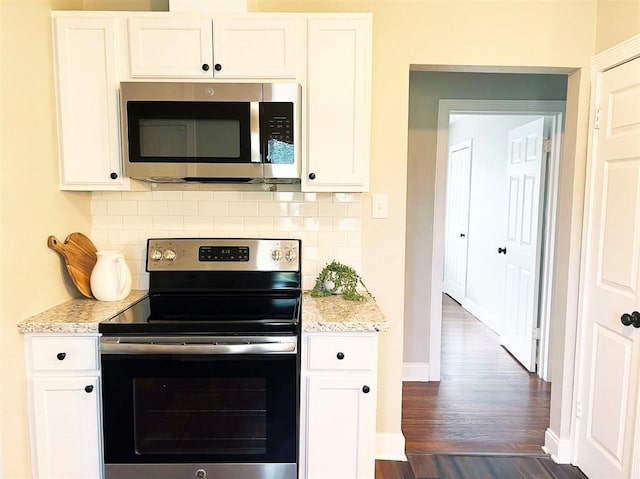 kitchen featuring white cabinets, stainless steel appliances, dark wood-type flooring, and decorative backsplash