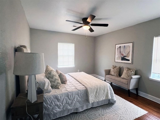 bedroom with multiple windows, ceiling fan, and dark wood-type flooring