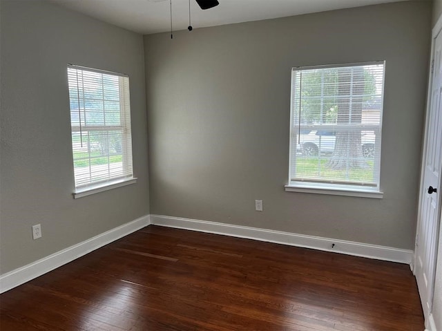 empty room with dark wood-type flooring, ceiling fan, and a healthy amount of sunlight