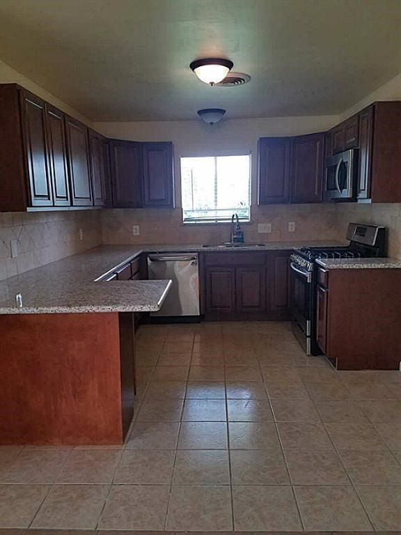 kitchen featuring dark brown cabinetry, appliances with stainless steel finishes, sink, and kitchen peninsula