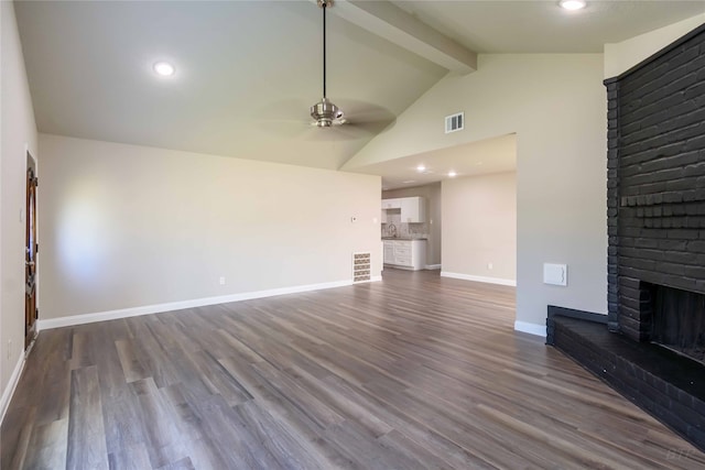 unfurnished living room with lofted ceiling with beams, a brick fireplace, ceiling fan, and hardwood / wood-style flooring