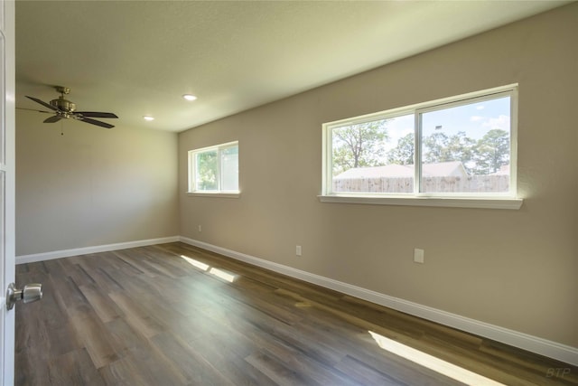 empty room with dark hardwood / wood-style flooring, ceiling fan, and a wealth of natural light