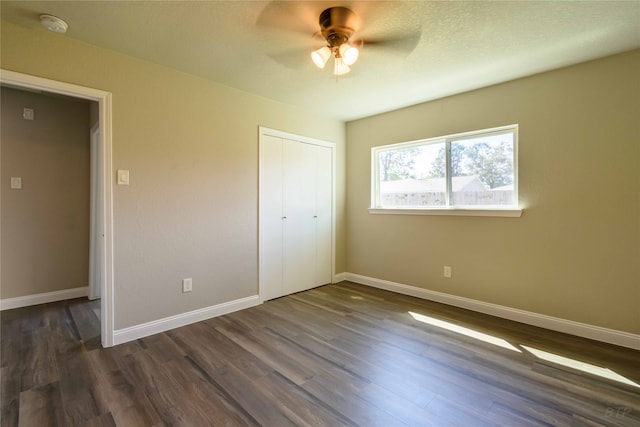 unfurnished bedroom featuring dark wood-type flooring, ceiling fan, and a closet