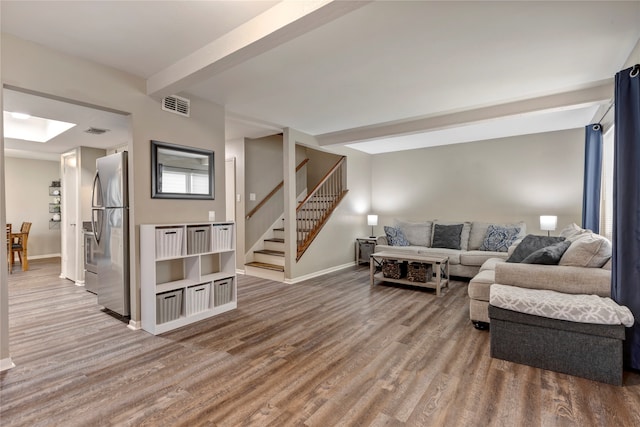 living room featuring beam ceiling, a skylight, and hardwood / wood-style flooring