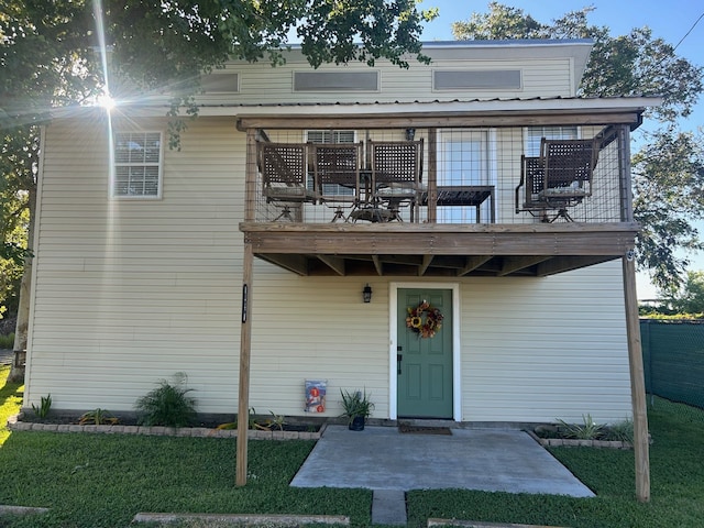 view of front of house featuring a front yard, a balcony, and a patio area