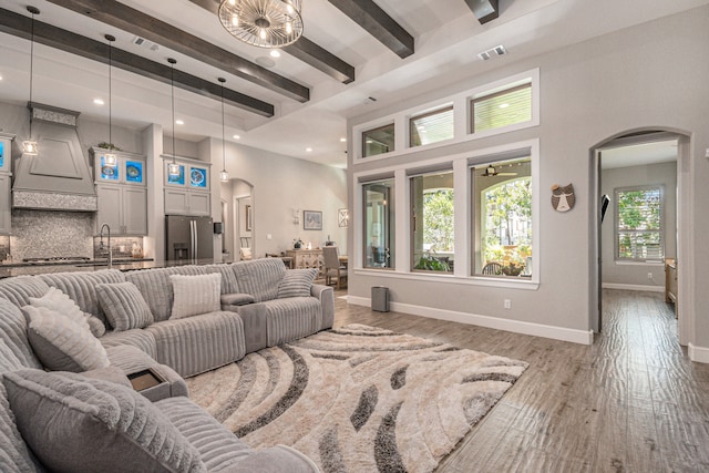 living room featuring wood-type flooring, sink, and beamed ceiling