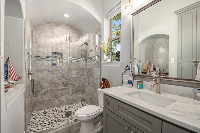 bathroom with a shower with door, vanity, and toilet