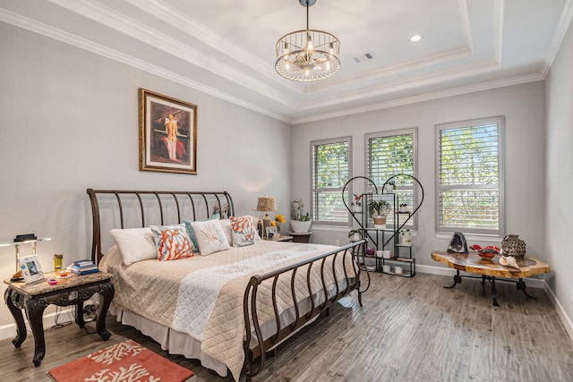 bedroom with multiple windows, wood-type flooring, ornamental molding, and a tray ceiling