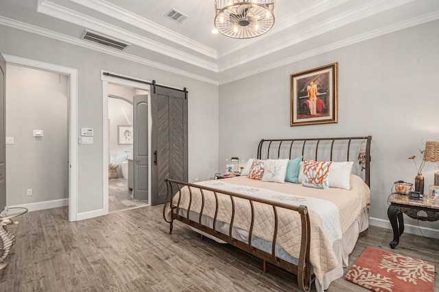 bedroom with a barn door, crown molding, a tray ceiling, and hardwood / wood-style flooring