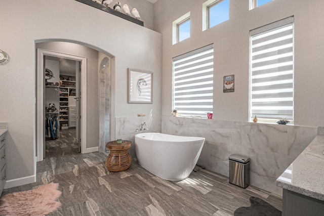 bathroom featuring tile walls, a tub, and vanity