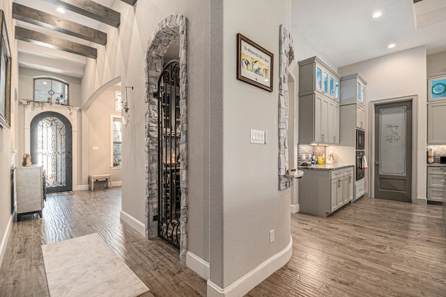 hallway featuring a towering ceiling, beamed ceiling, and dark hardwood / wood-style floors